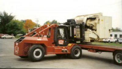 Louis P. Cote, Inc. riggers unload a piece of heavy machinery with a forklift.