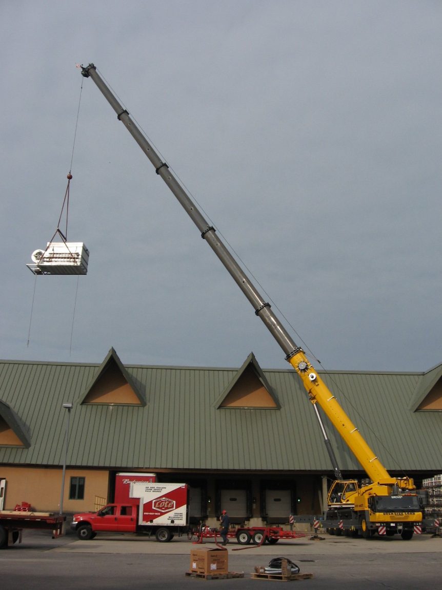 Louis P. Cote, Inc. uses a crane to hoist a rooftop unit into position.
