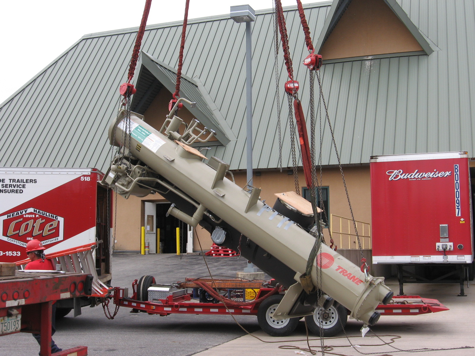 Louis P. Cote, Inc. uses a crane to lift heavy equipment off one of it's flatbed trailers after transport.