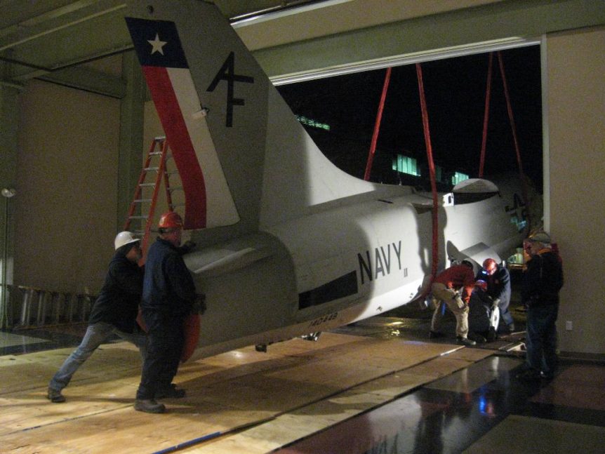 Louis P. Cote, Inc.'s riggers use a crane to move the body of a 1956 U.S. Navy XF8U-2 Crusader jet into the McAuliffe-Shepard Discovery Center in Concord NH