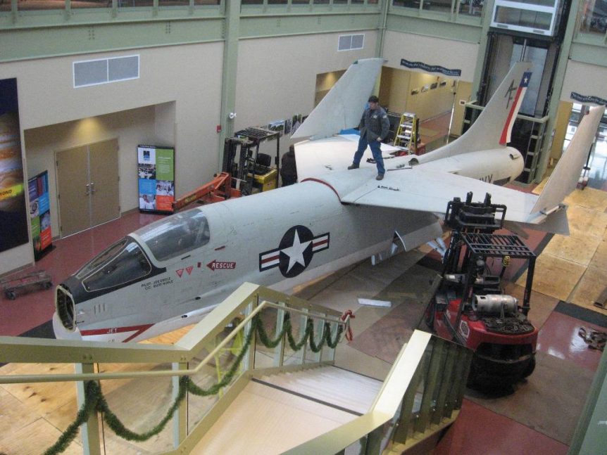 Louis P. Cote, Inc.'s riggers use two forklifts to attach the wings to the body of a 1956 U.S. Navy XF8U-2 Crusader jet inside of the McAuliffe-Shepard Discovery Center in Concord NH