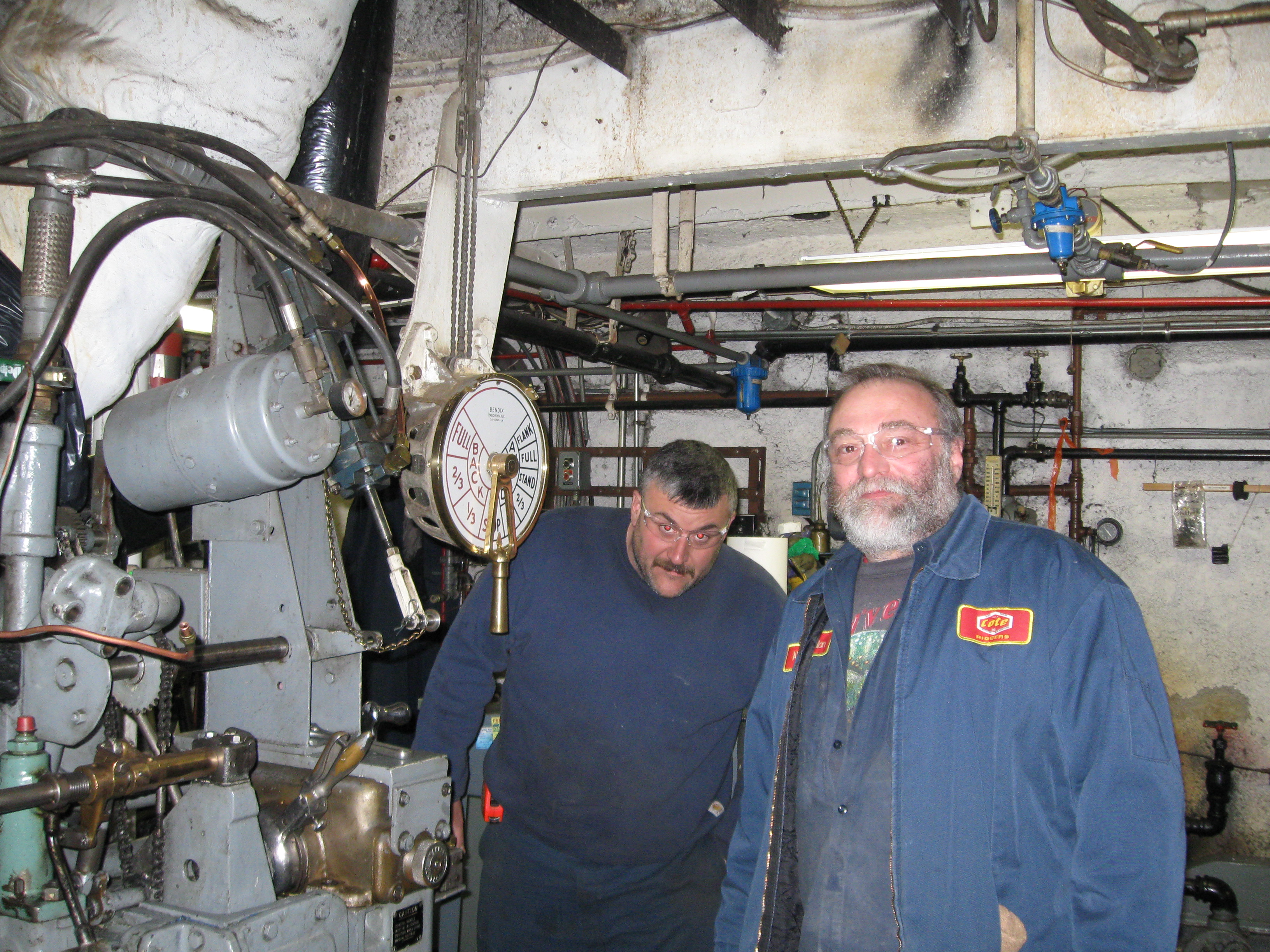 Louis P. Cote, Inc.'s riggers stand next to the engine controls in the MS Mount Washington Cruise ship after removing the engine.